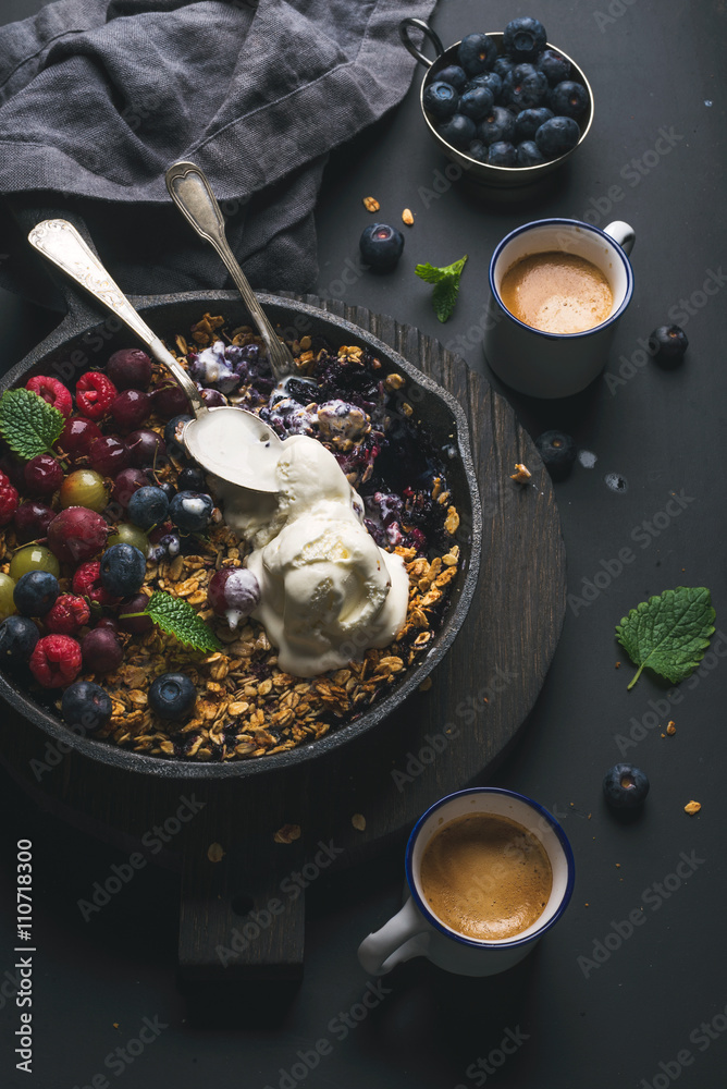 Healthy breakfast. Oat granola crumble with fresh berries, seeds and ice-cream in iron skillet pan o