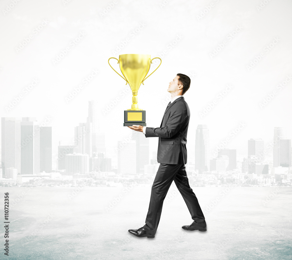 Businessman carrying cup trophy