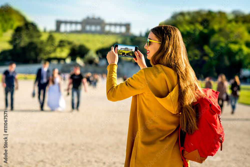 Young female tourist photographing with phone Gloriette building in Schoenbrunn palace in Vienna