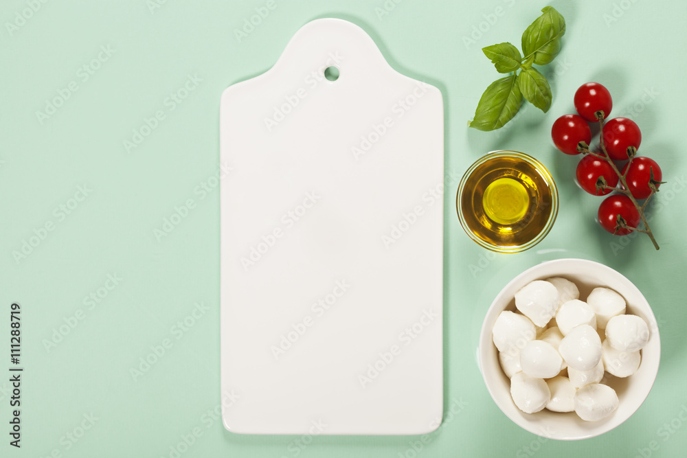 White ceramic serving board and salad ingredients over light blu