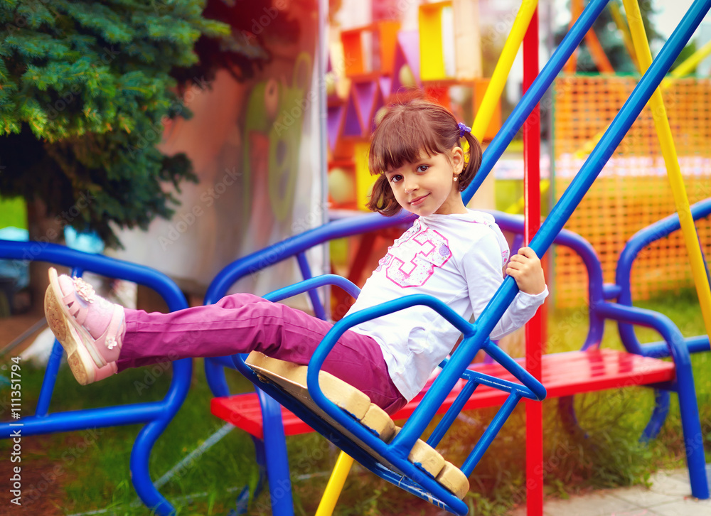 cute happy girl having fun on swings at playground