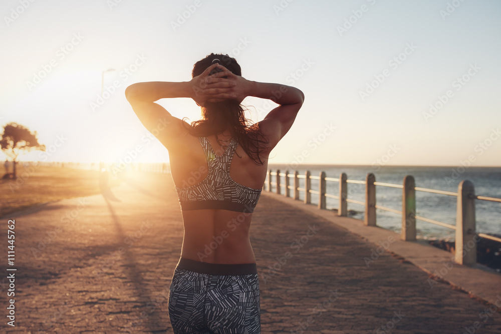 日落时分在海边散步的女运动员