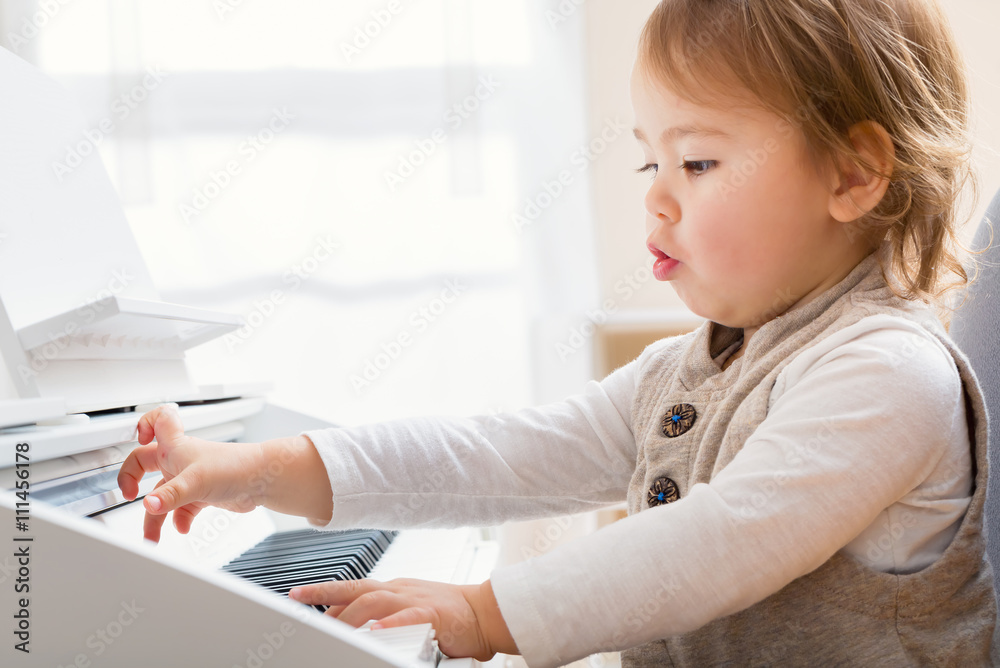 Little toddler girl playing piano