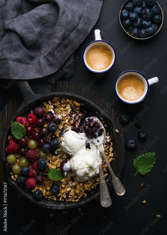 Healthy breakfast. Oat granola crumble with fresh berries, seeds and ice-cream in iron skillet pan o