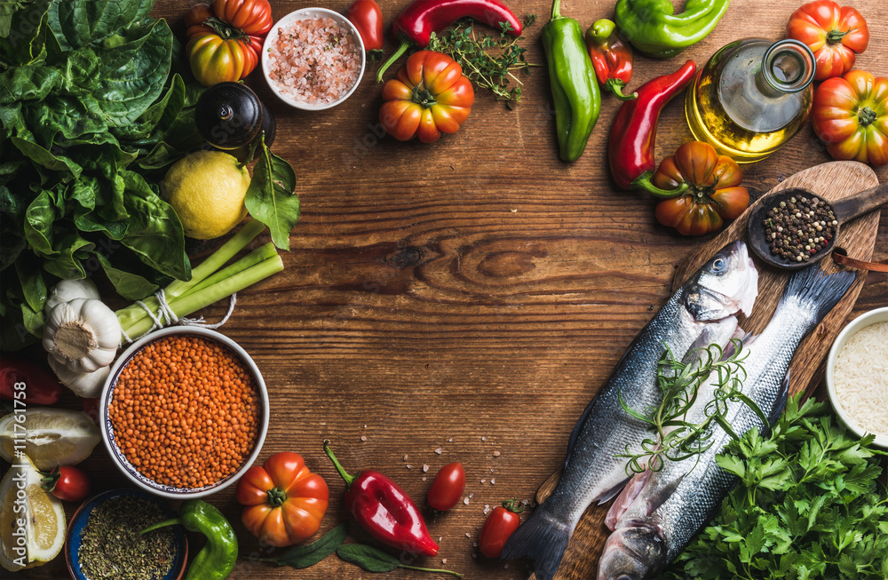 Ingredients for cooking healthy dinner. Raw uncooked seabass fish with vegetables, grains, herbs and