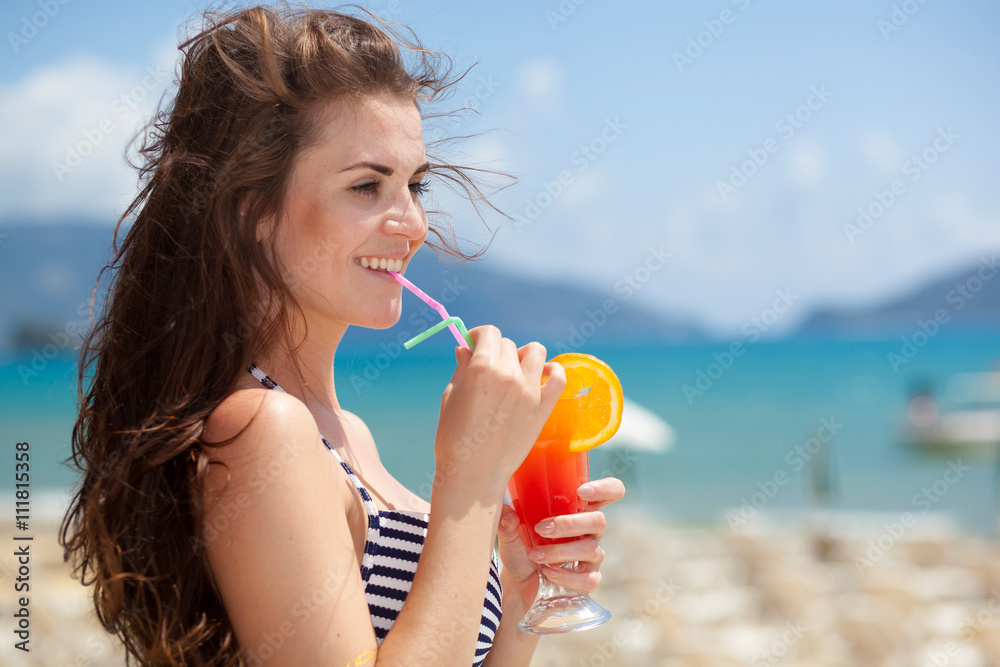 Woman with cocktail on the beach during tropical vacation