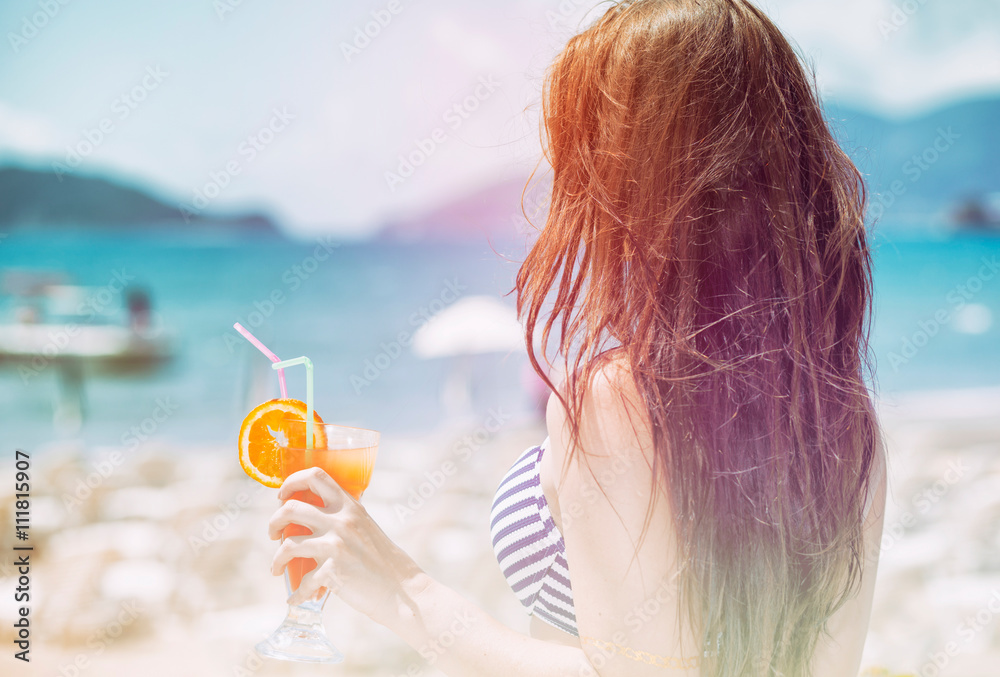 Woman with cocktail on the beach during tropical vacation