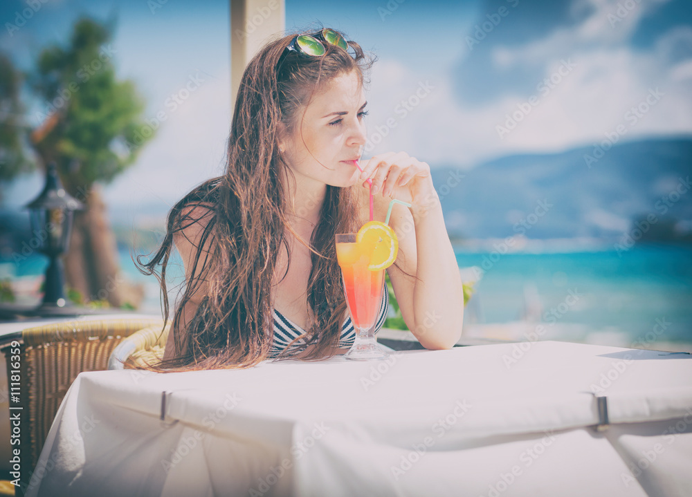 Woman with cocktail in the beach bar during tropical vacation