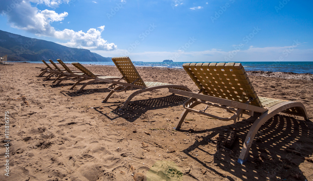 Empty lounge chairs on sandy beach before summer season