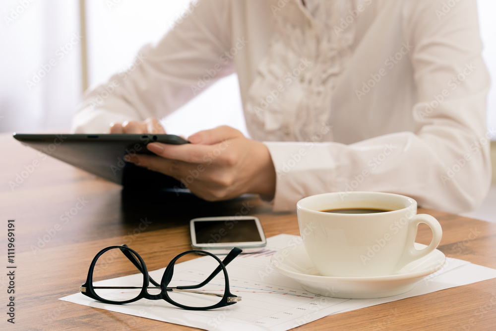 Businesswoman using tablet and drink coffee at desk