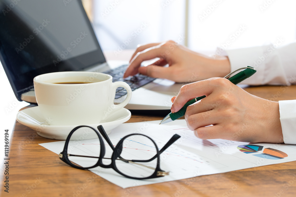 Businesswoman using laptop and  writing at desk