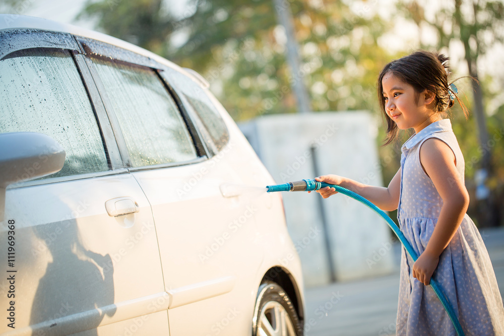 Happy Asian girl washing car on water splashing and sunlight at home