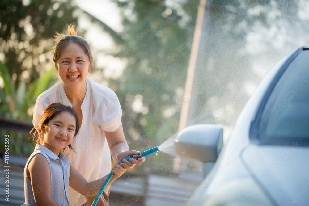 Happy Asian girl helping her mother washs car at home