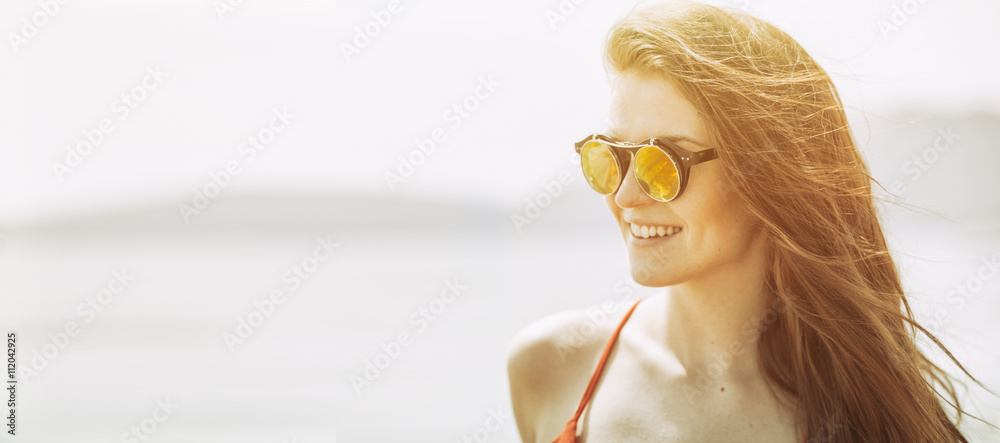 Young woman on the beach in hot summer sun light