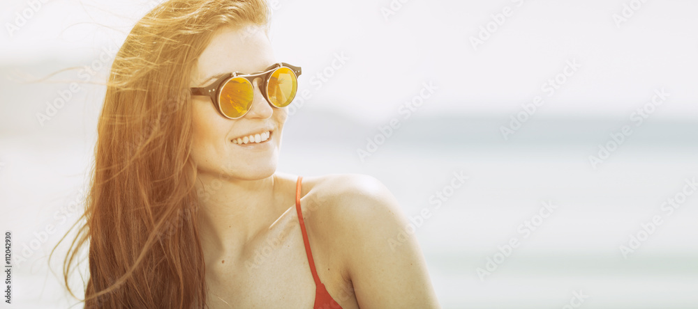 Young woman on the beach in hot summer sun light