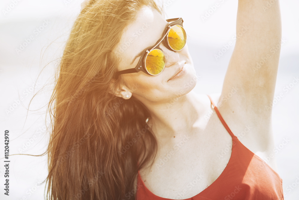 Young woman on the beach in hot summer sun light