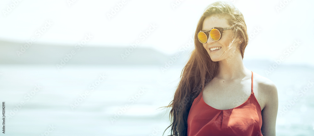 Young woman on the beach in hot summer sun light