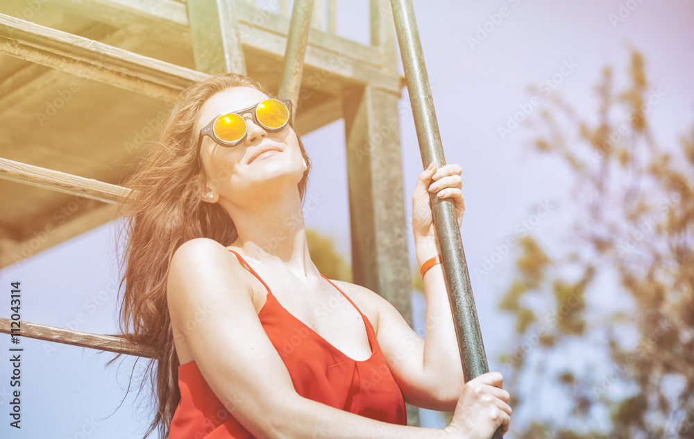 Young woman on the beach in hot summer sun light