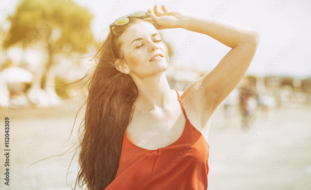 Young woman on the beach in hot summer sun light