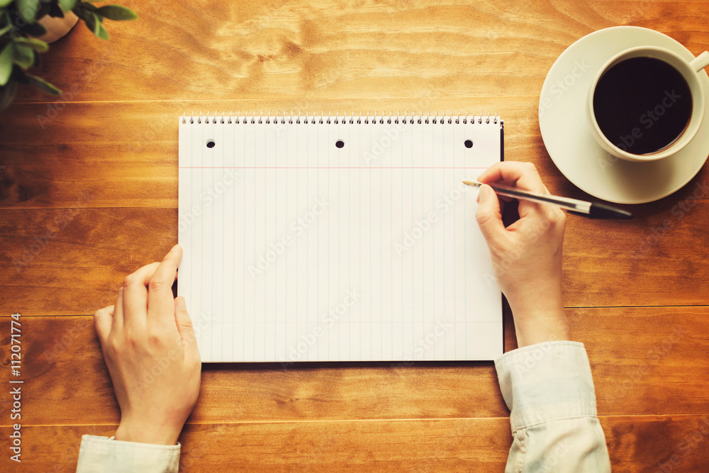 Hands of a person writing in a small notepad