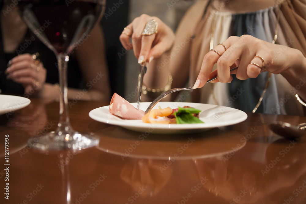 Young women are enjoying the meal with a glass of wine