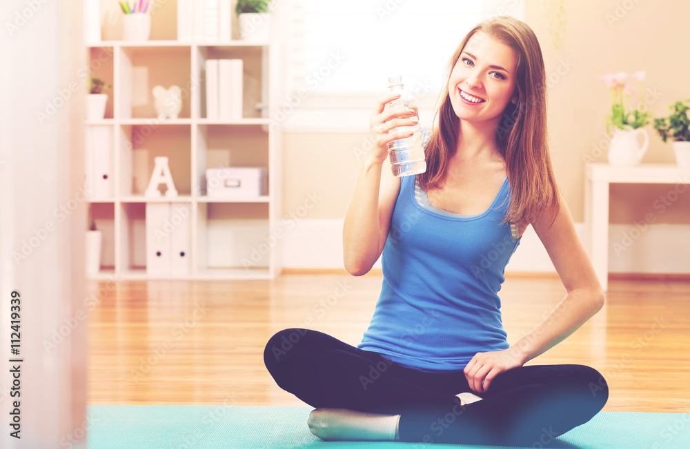 Happy athletic woman with a bottle of water in her studio