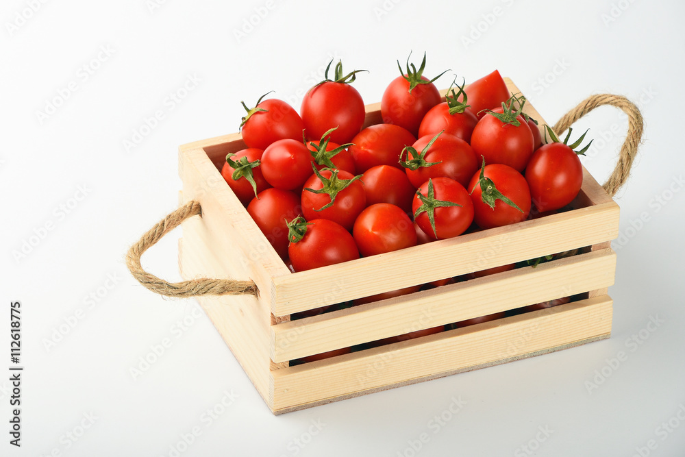 Red cherry tomatoes in wooden box over white