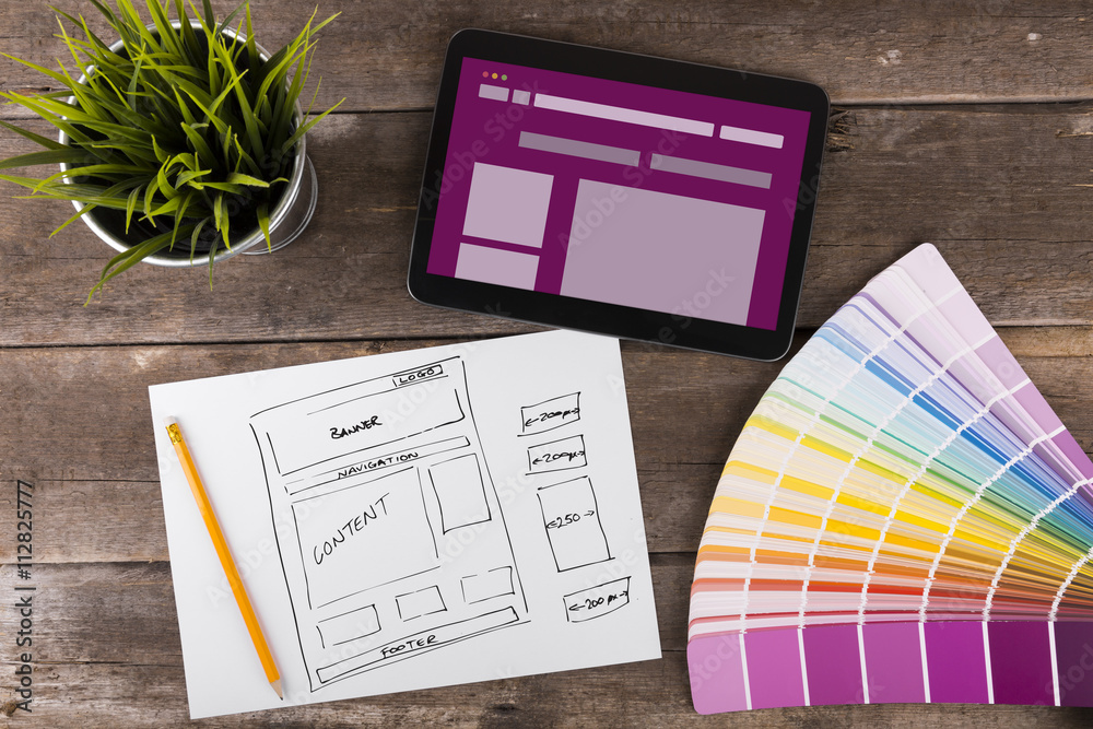 木桌上的网站线框草图和数字平板电脑