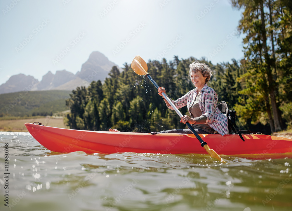 Mature woman paddling a kayak in lake