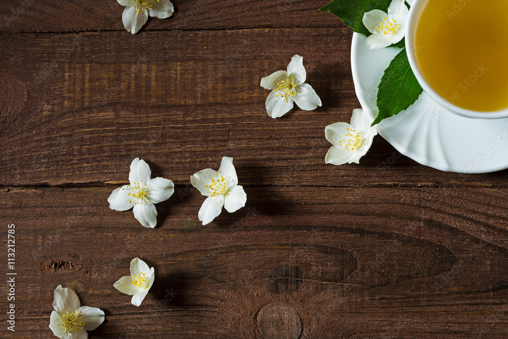 A cup of jasmine tea with jasmine flowers on a wooden background