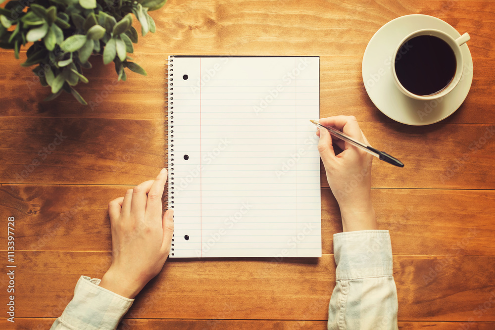 Hands of a person writing in a small notepad