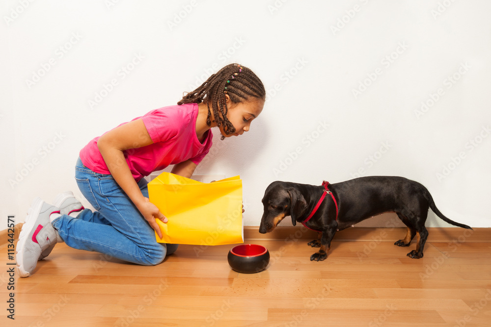 Black girl put food on dog plate