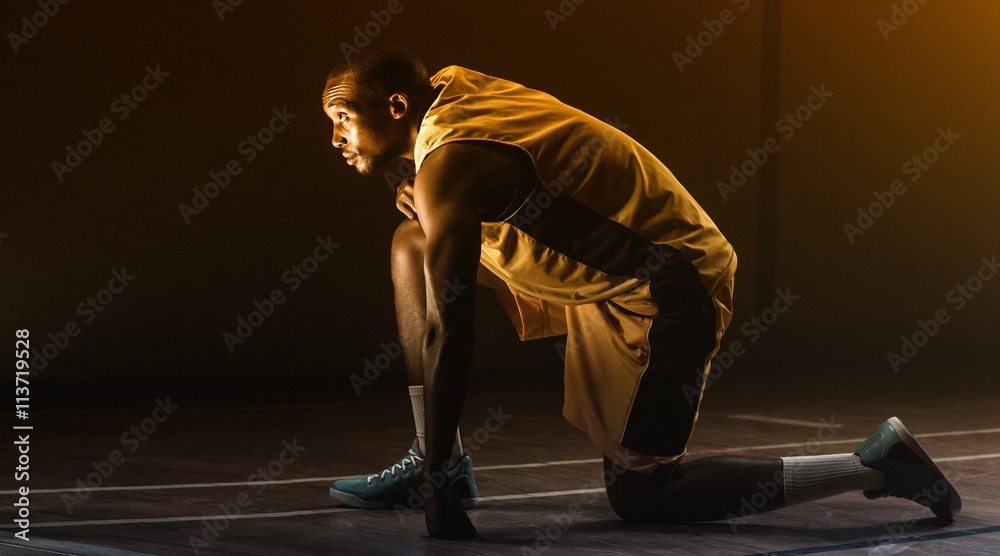 Basketball player with knee on the floor 