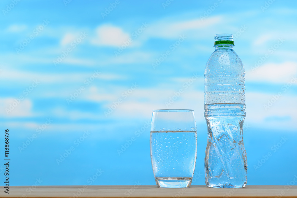 Fresh and clean drinking water in bottle and glass on sky background