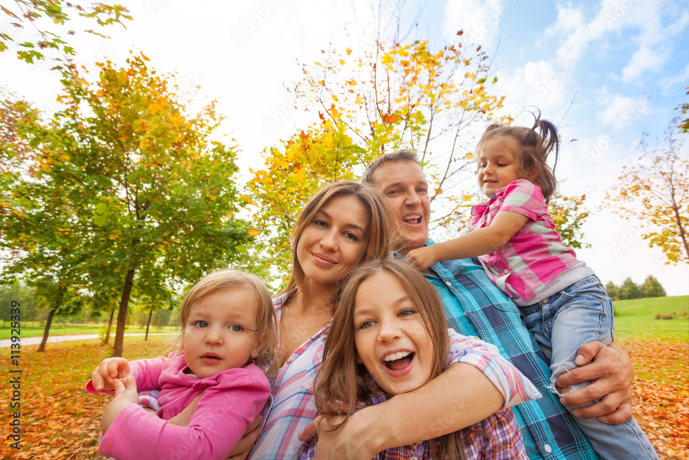 Happy family play in autumn park hug little kids