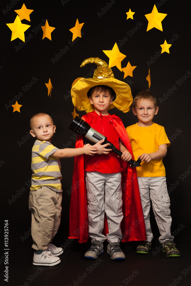 Three boys playing stargazers with a telescope