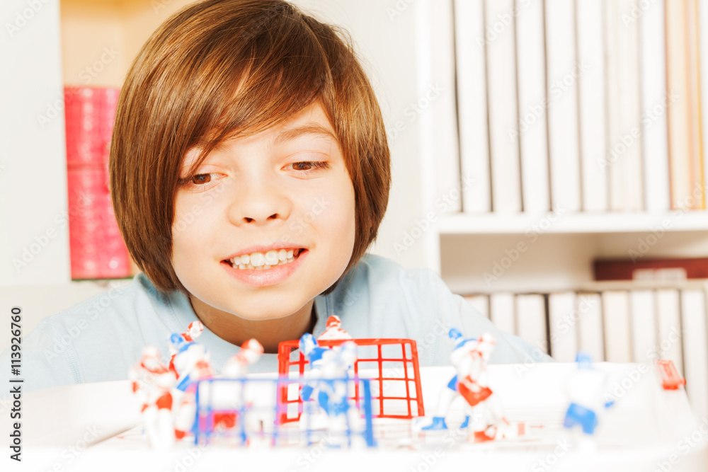 Smiling boy playing ice hockey table board game