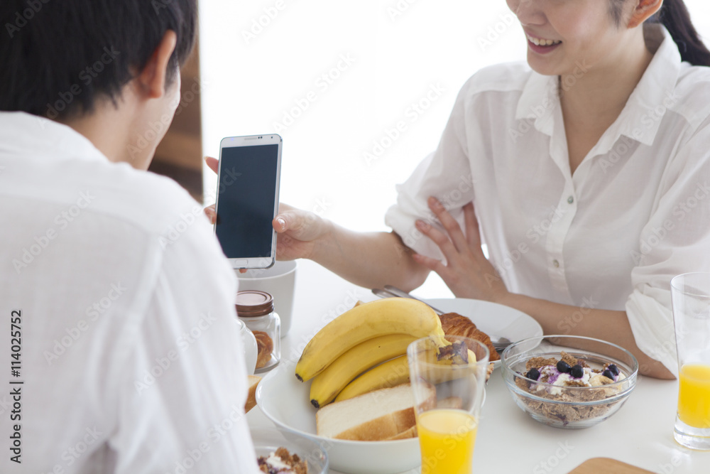 女人在餐桌上向男人展示智能手机