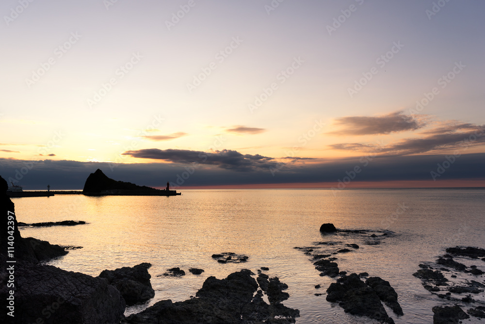 rock beach near tranquil sea at sunrise