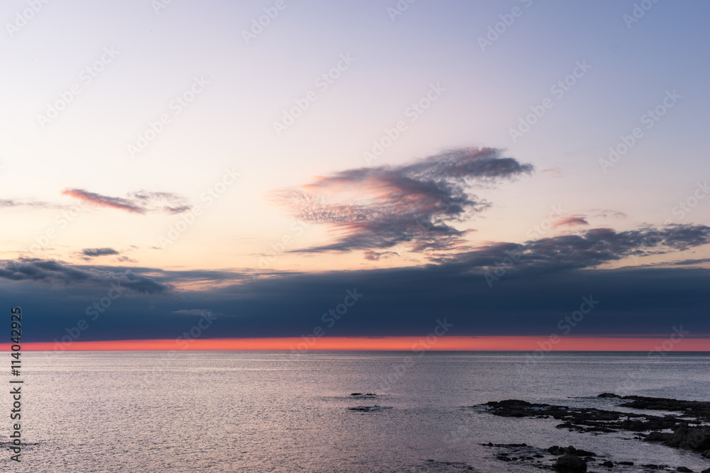 日出时宁静海边的岩石海滩