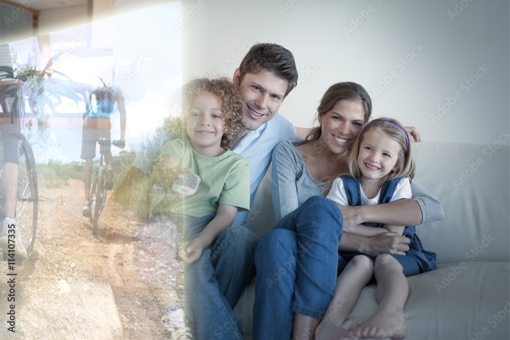 Composite image of smiling family watching tv together