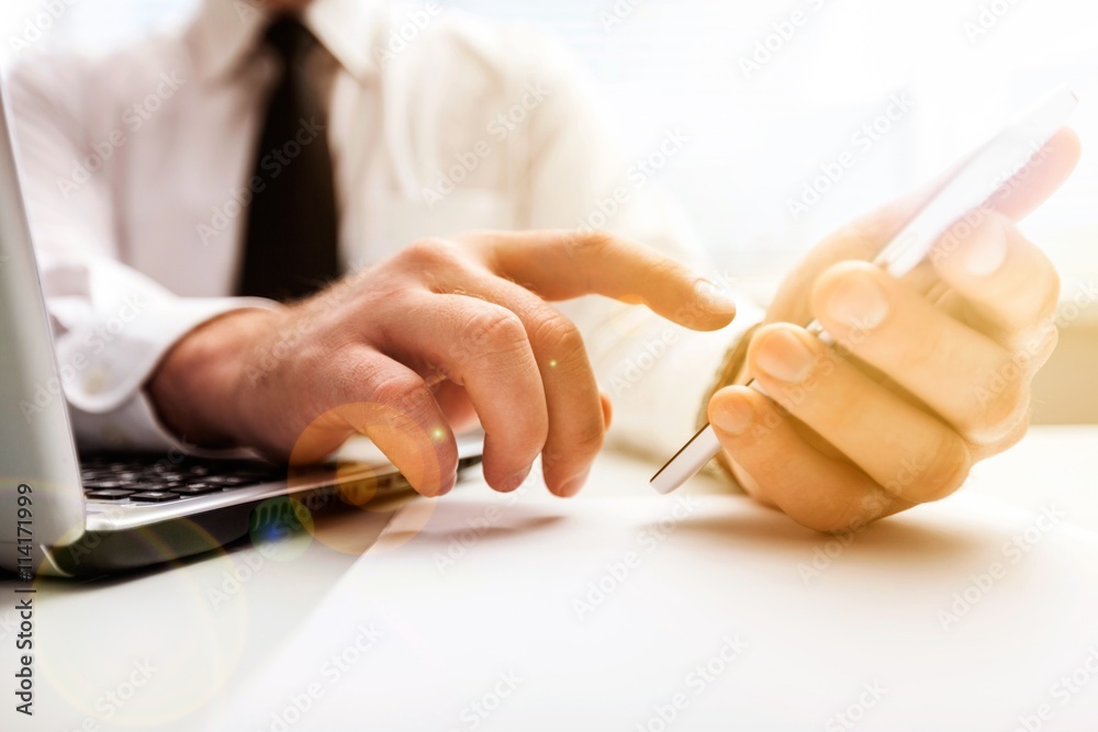 Business man hand working on phone and laptop.