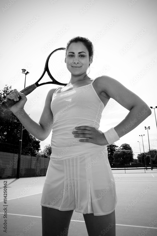 Pretty tennis player holding racket smiling at camera