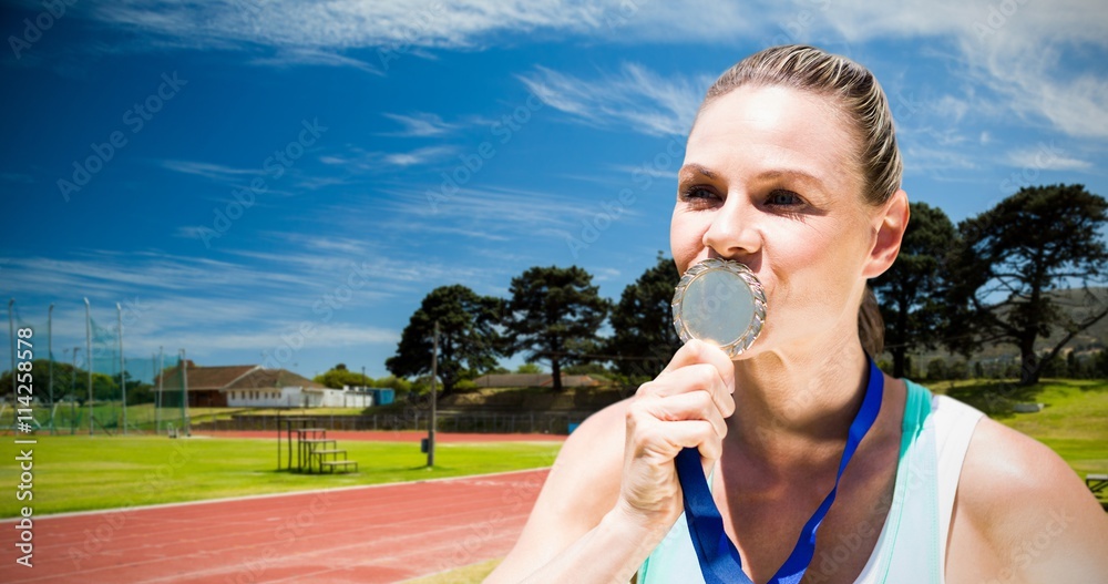 Composite image of portrait of sportswoman kissing a medal 