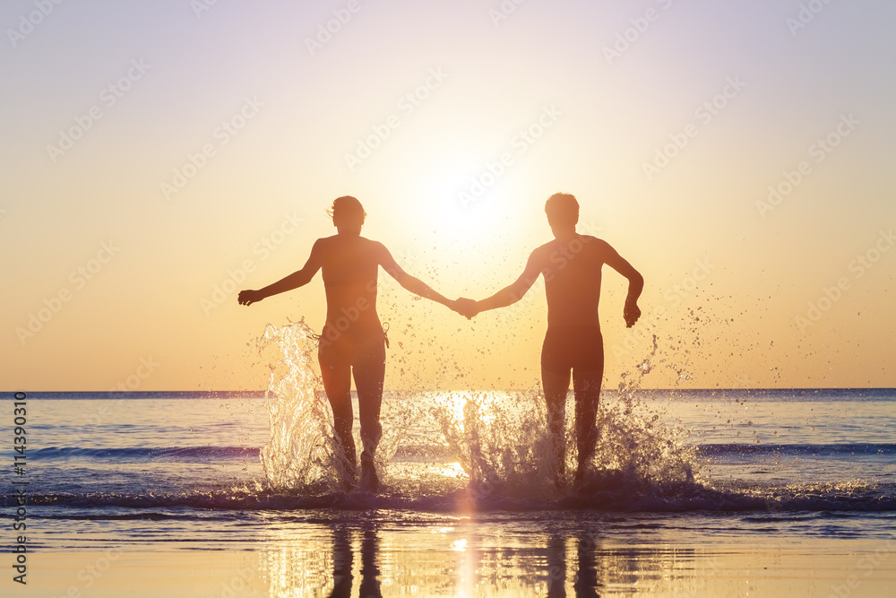 Happy couple running to the sea with splashes of water