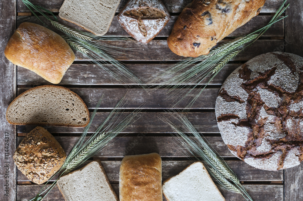 Verschiedene Brotsorten auf einem Holztisch / Stillleben von verschiedenen Brotsorten mit Getreideae