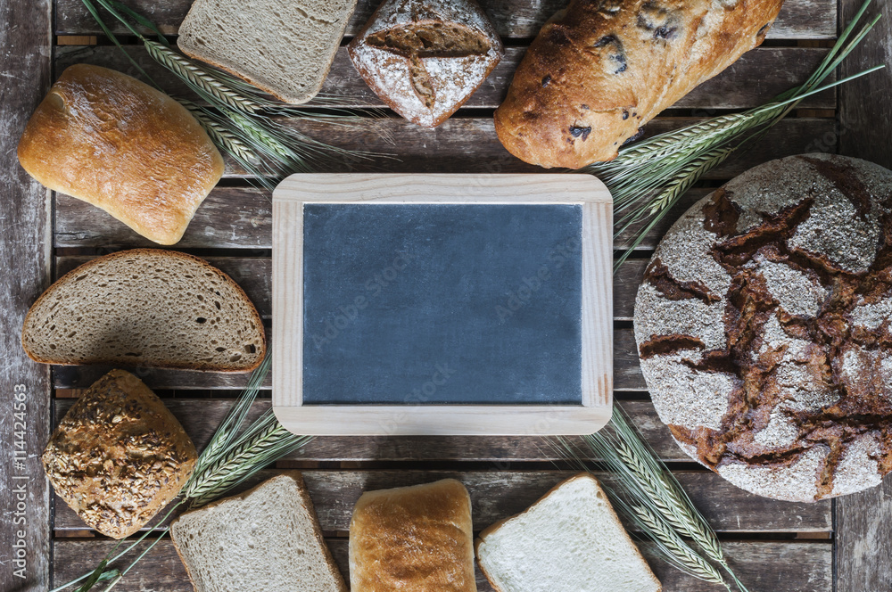 Verschiedene Brotsorten mit einer Tafel auf einem Holztisch / Verschiedene Brotsorten in der Mitte l