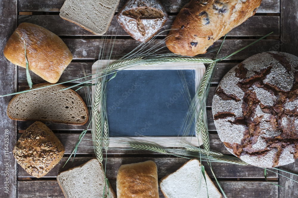 Verschiedene Brotsorten mit einer Tafel auf einem Holztisch / Verschiedene Brotsorten in der Mitte l