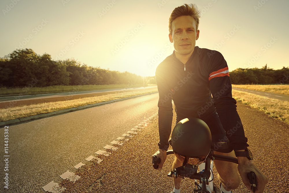 Bicyclist pausing at highway with helmet off