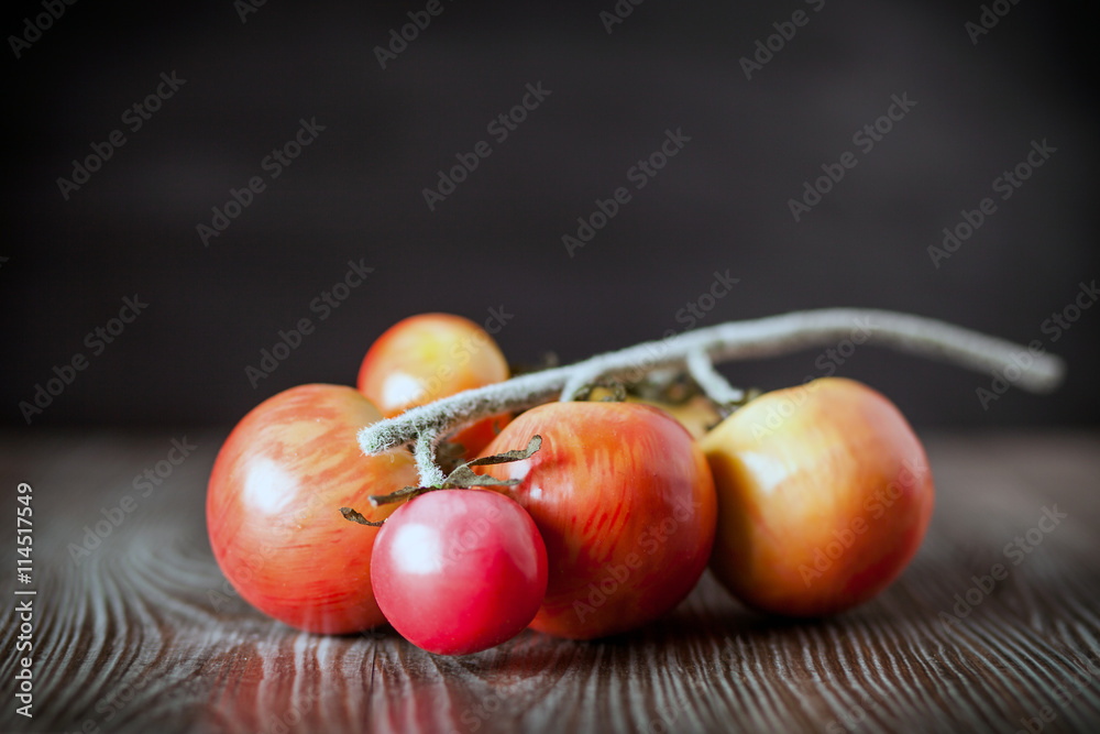 Tomatoes on branch. Wooden board dark background front view